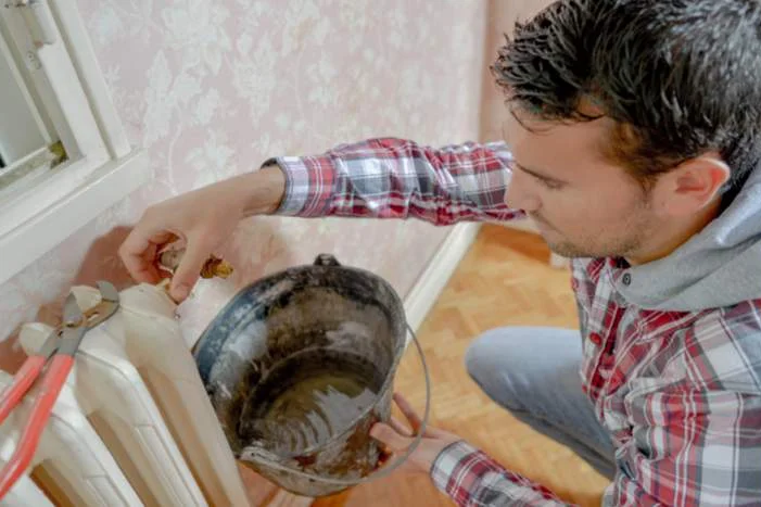 Person entlüftet Heizkörper mit Zange